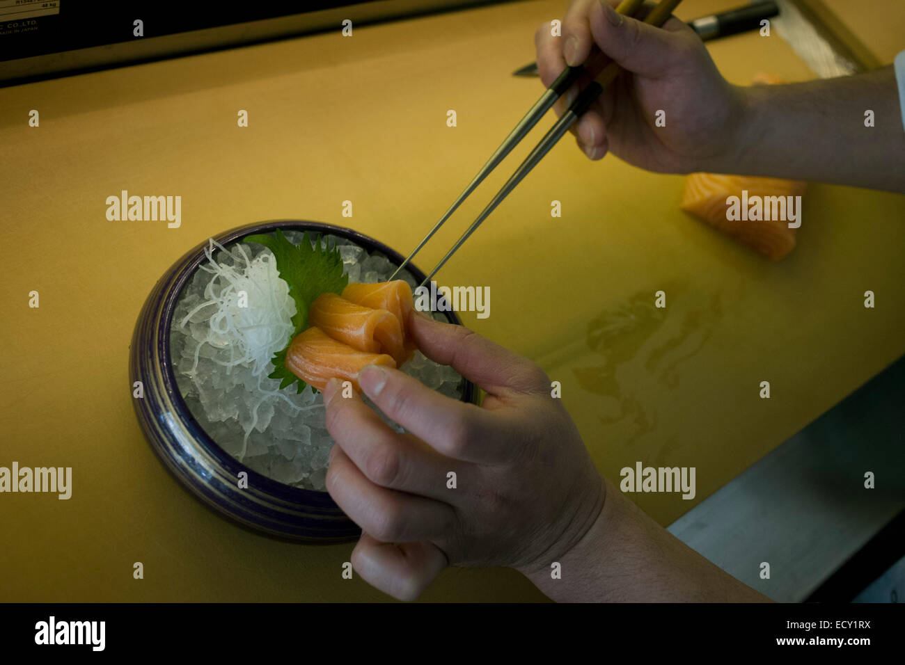 Dettaglio di un cuoco le mani, preparare il salmone con pinze in 'o', un ristorante di sushi in centro a Londra. Foto Stock