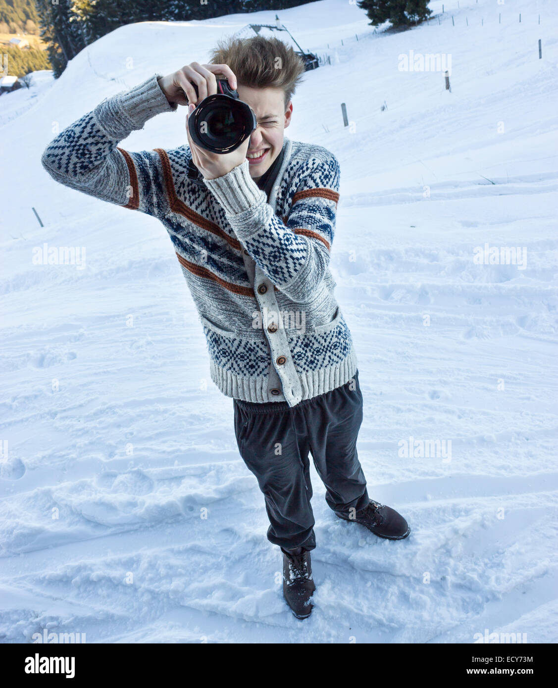 Giovane uomo nella neve di scattare una foto con una fotocamera reflex digitale, Hochbrixen, Brixen im Thale, Tirolo, Austria Foto Stock
