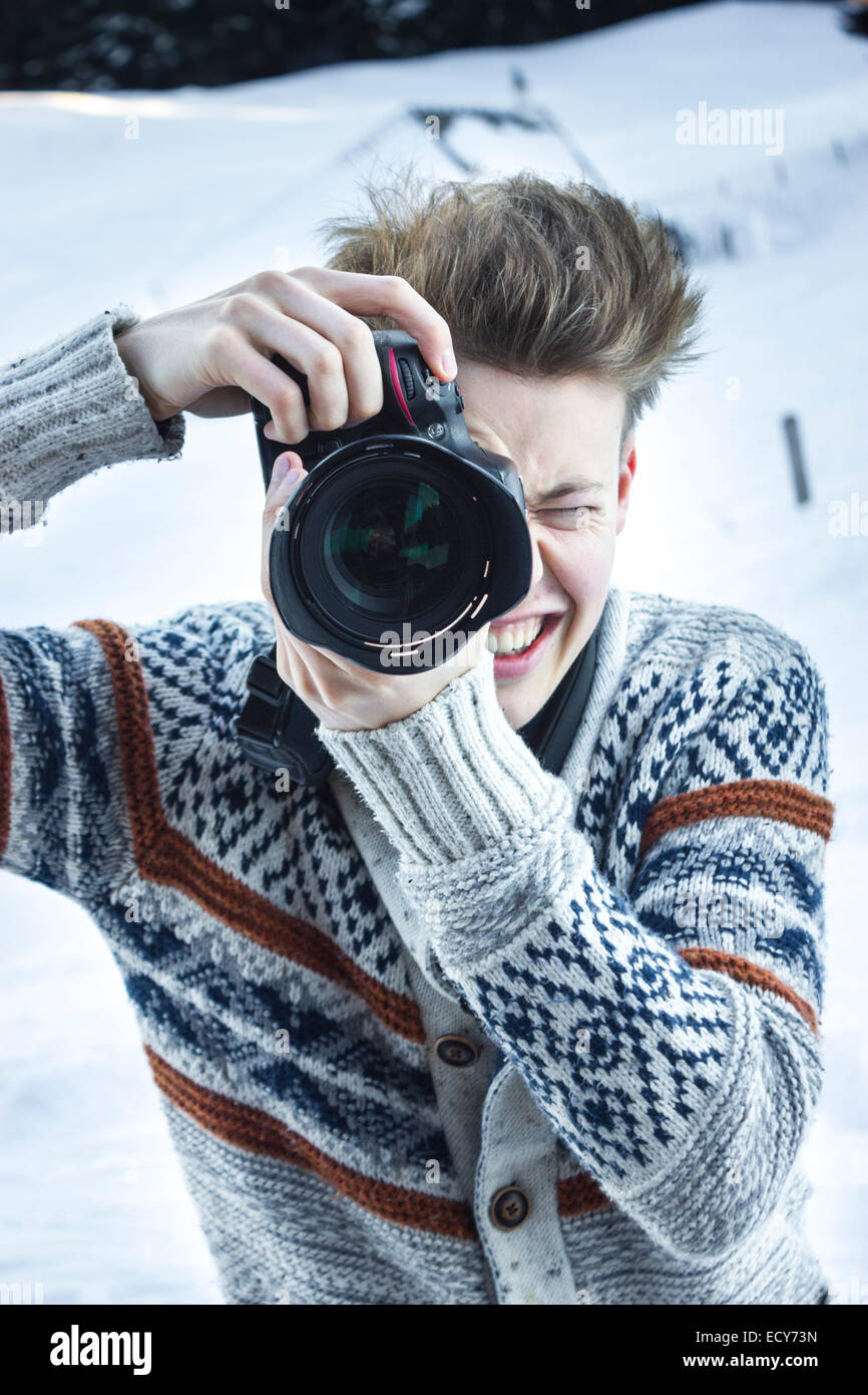 Giovane uomo nella neve di scattare una foto con una fotocamera reflex digitale, Hochbrixen, Brixen im Thale, Tirolo, Austria Foto Stock