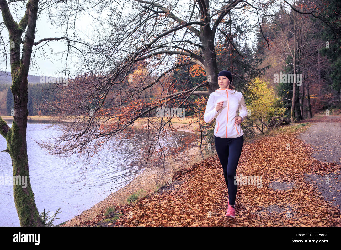 Donna jogging lungo un lago, Scheibe-Alsbach, Turingia, Germania Foto Stock