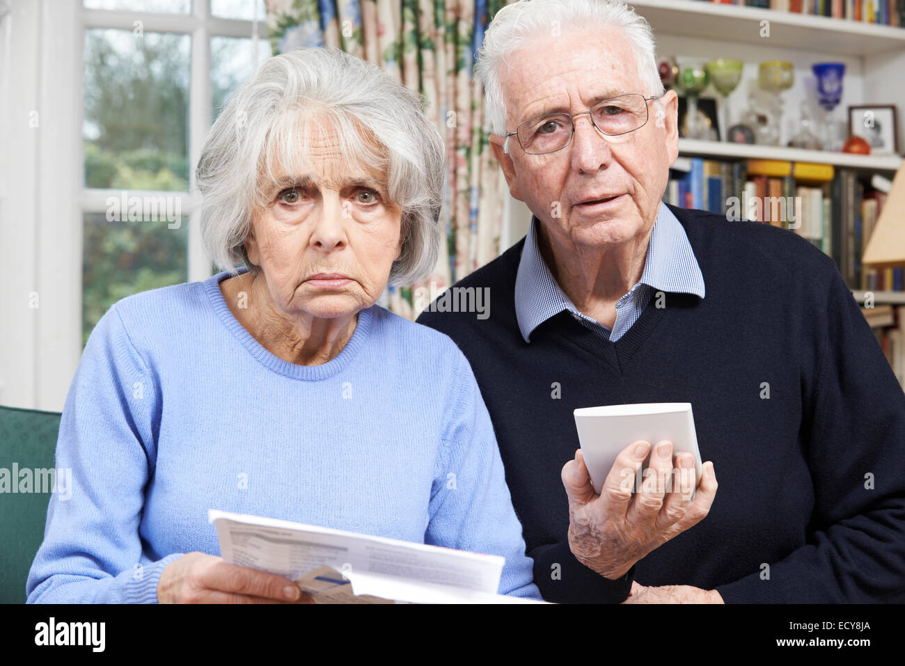 Coppia senior a casa con le bollette preoccupati delle finanze personali Foto Stock