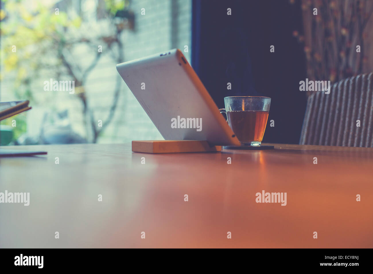 Tablet in piedi sulla tavola con un bicchiere di tè a casa Foto Stock