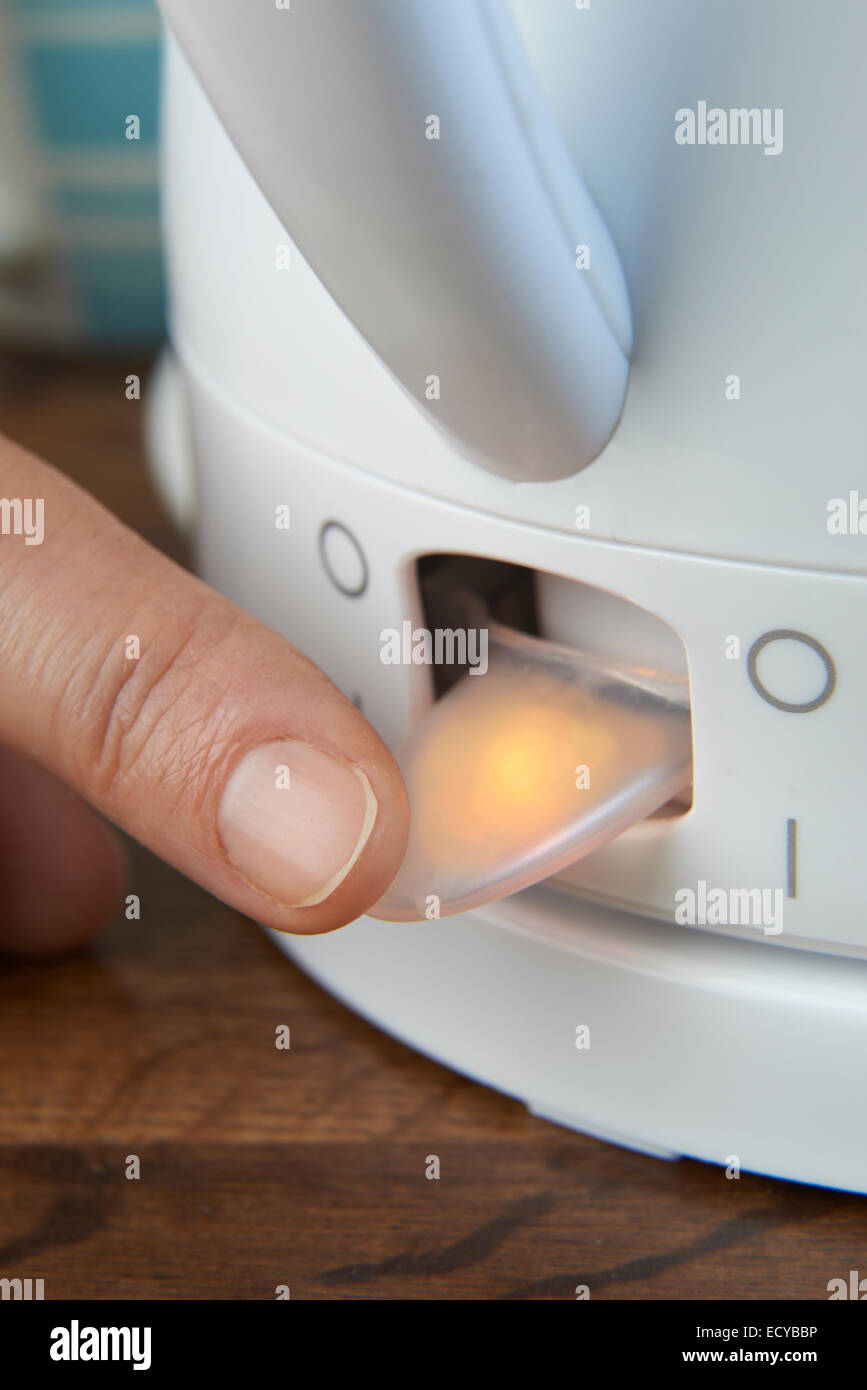 Close up della donna di accendere l'interruttore di alimentazione del bollitore Foto Stock