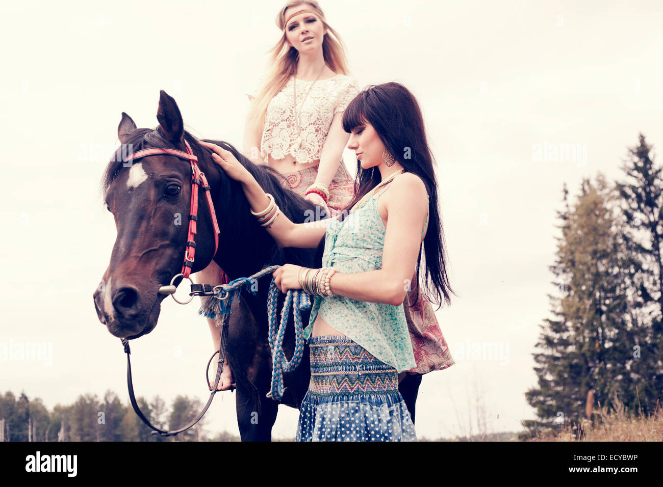 Donne caucasici petting e equitazione all'aperto Foto Stock