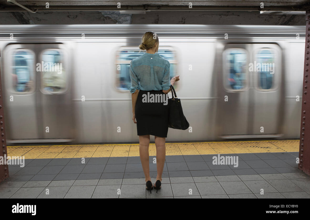 Caucasian woman standing passando vicino alla metropolitana in una stazione ferroviaria Foto Stock