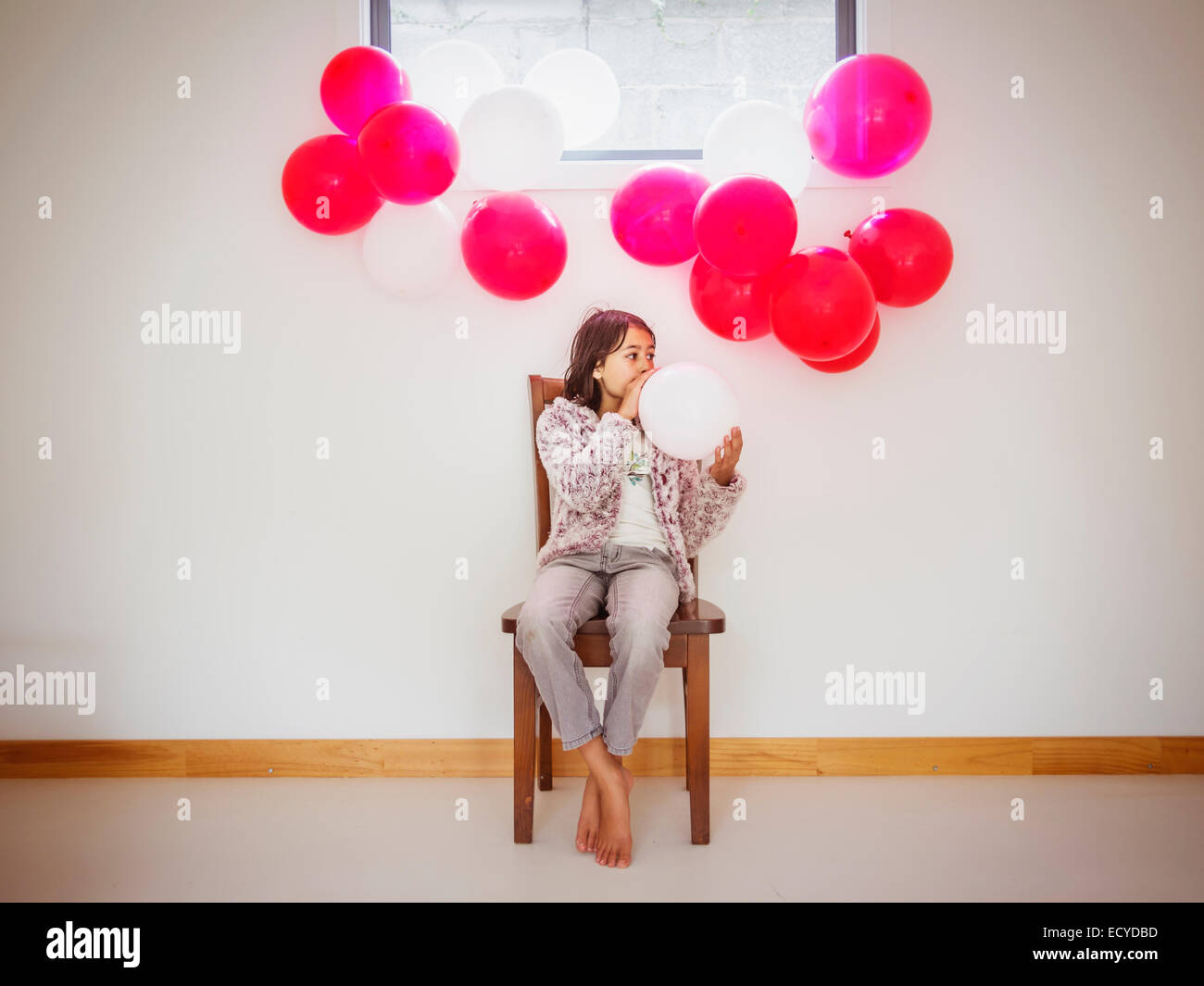 Razza mista ragazza soffia su palloncini per party Foto Stock