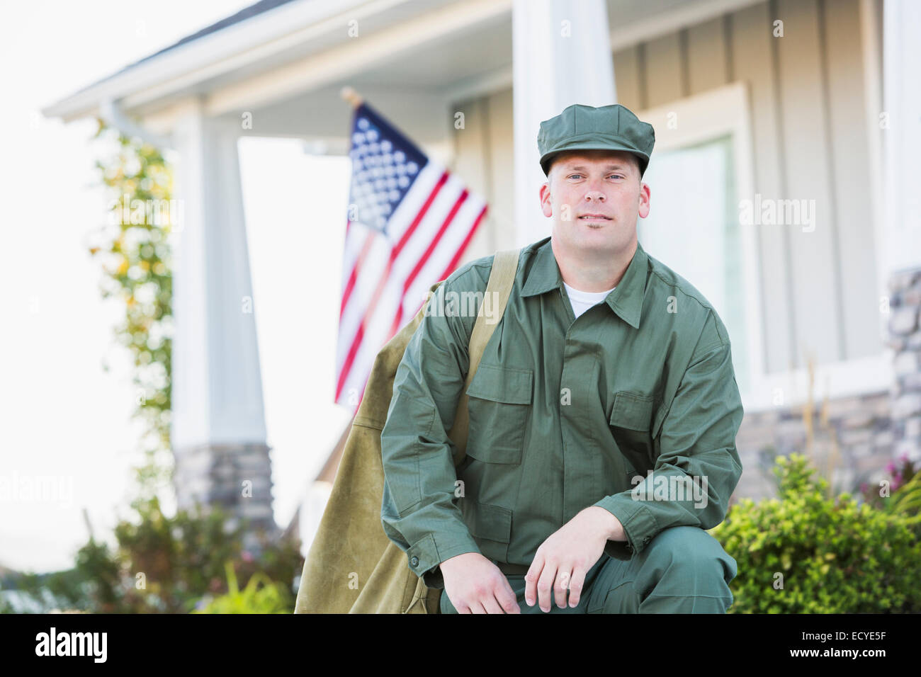 Soldato caucasica inginocchiato vicino casa Foto Stock
