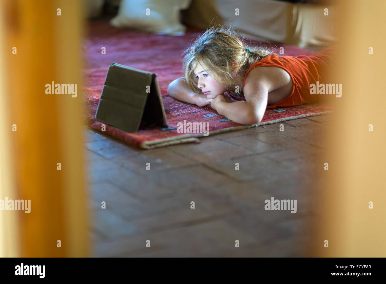 Ragazza caucasica guardando la tavoletta digitale sul pavimento Foto Stock