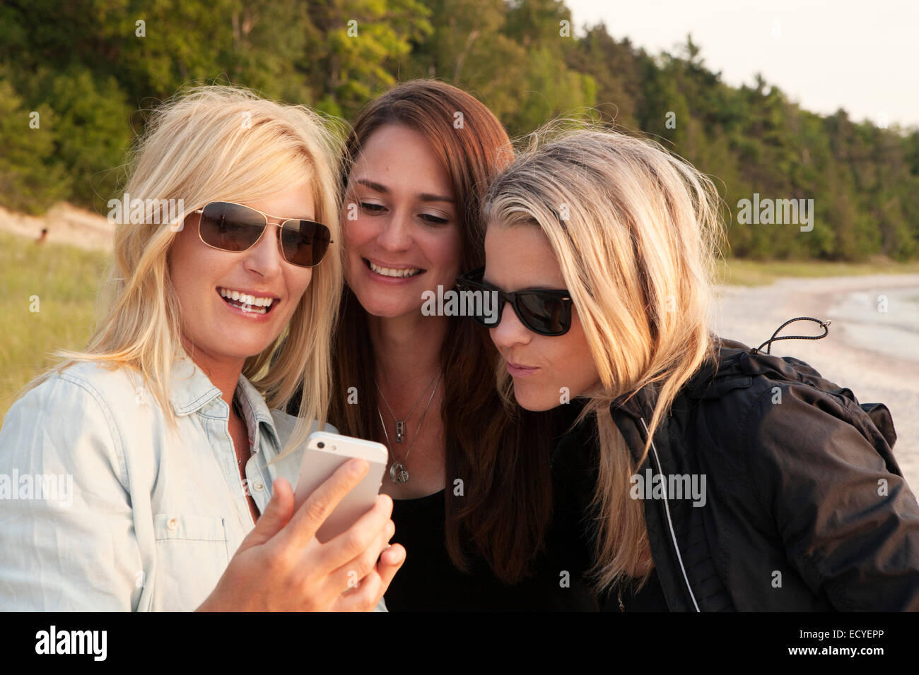 Donne caucasici tramite telefono cellulare all'aperto Foto Stock