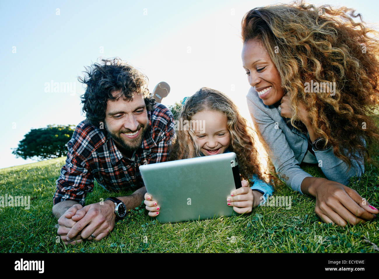 La famiglia tramite tavoletta digitale nel campo erboso Foto Stock