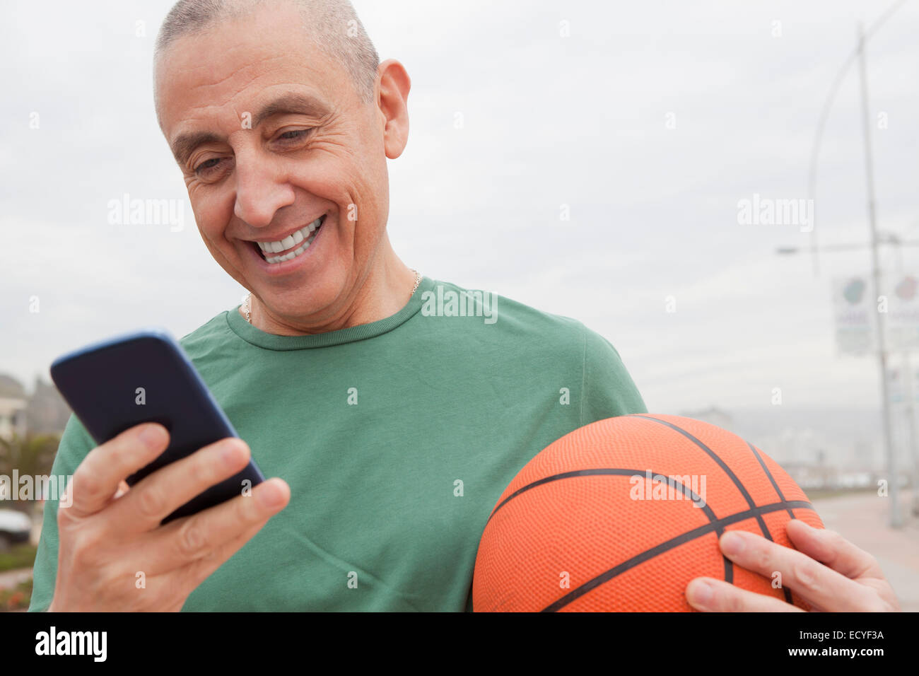 Ispanico uomo senior con basket tramite telefono cellulare Foto Stock