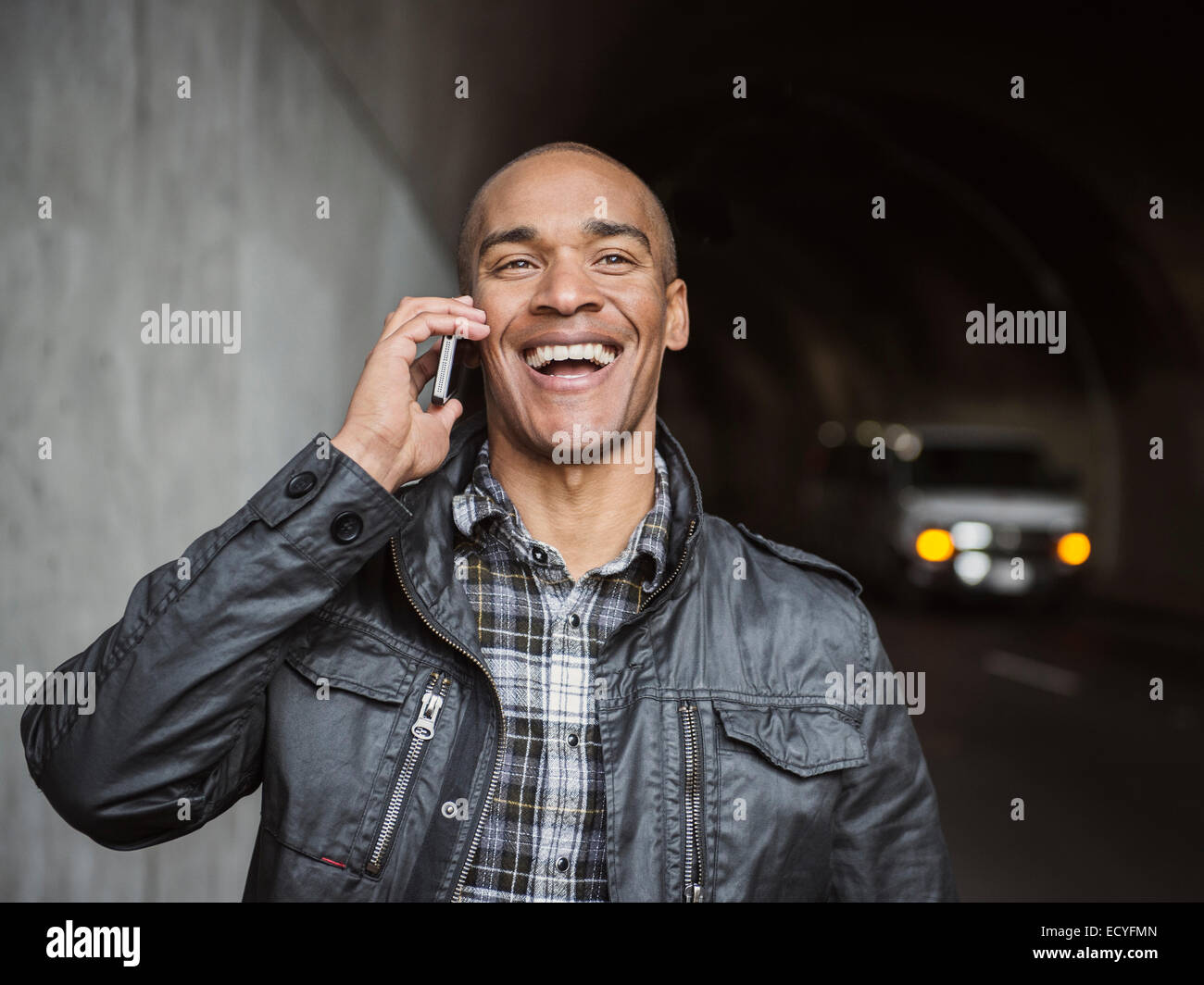 Uomo nero parlando al cellulare nel tunnel urbano Foto Stock