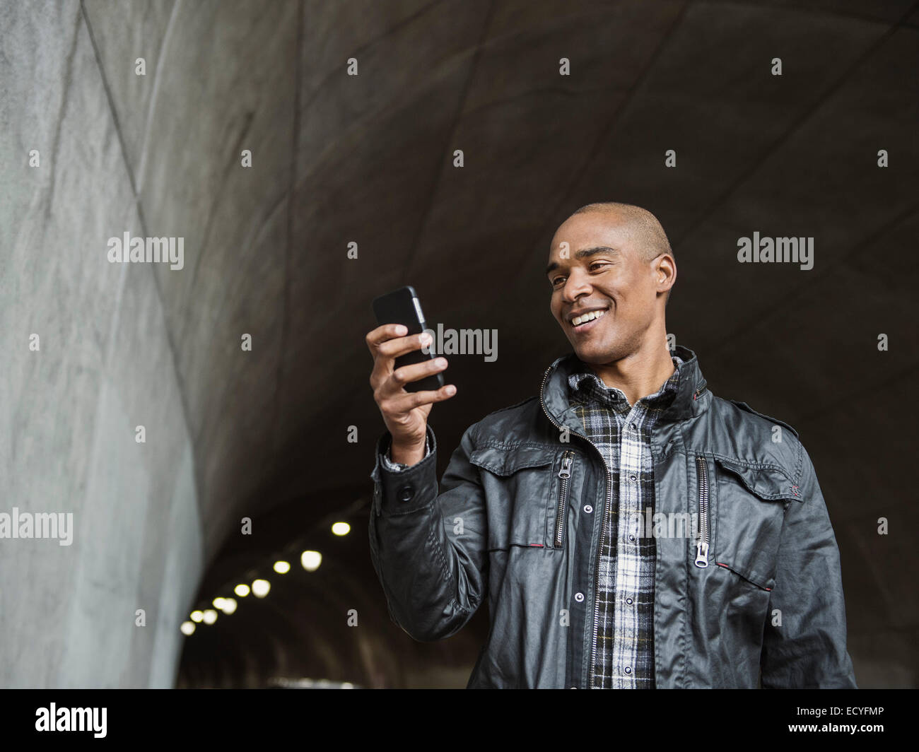 Uomo nero utilizzando il cellulare in tunnel urbano Foto Stock