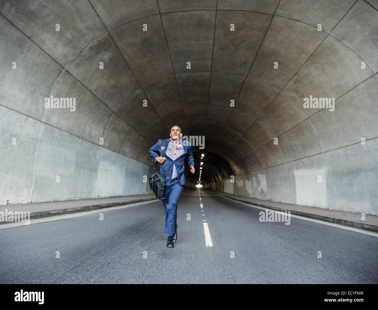 Imprenditore nero in esecuzione con valigetta in tunnel urbano Foto Stock