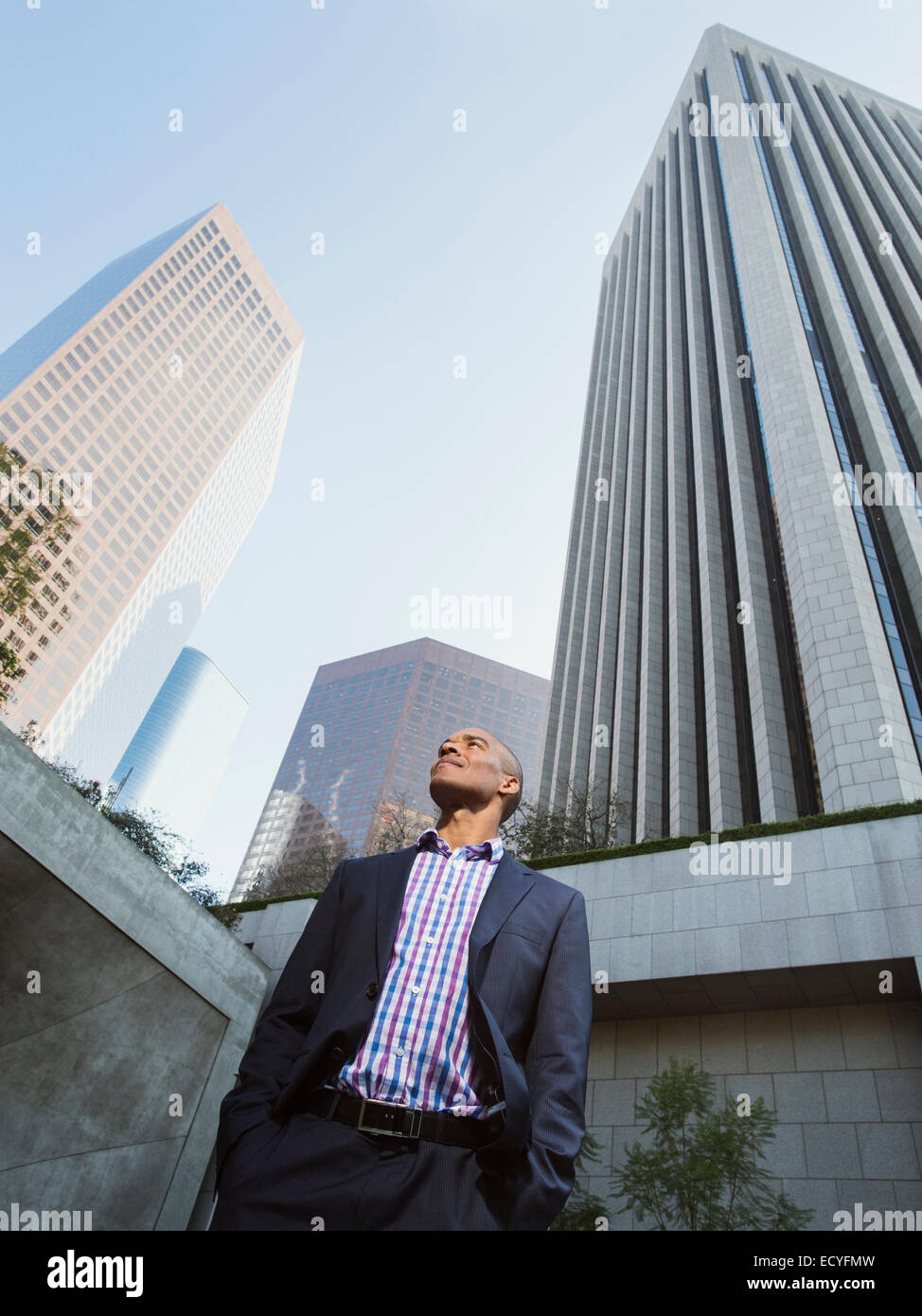 Basso angolo vista di imprenditore nero in piedi al di fuori del grattacielo urbano Foto Stock
