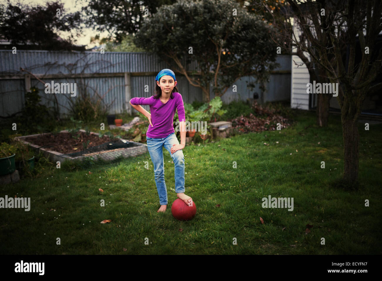 Razza mista ragazza che gioca con la palla calcio in cortile Foto Stock