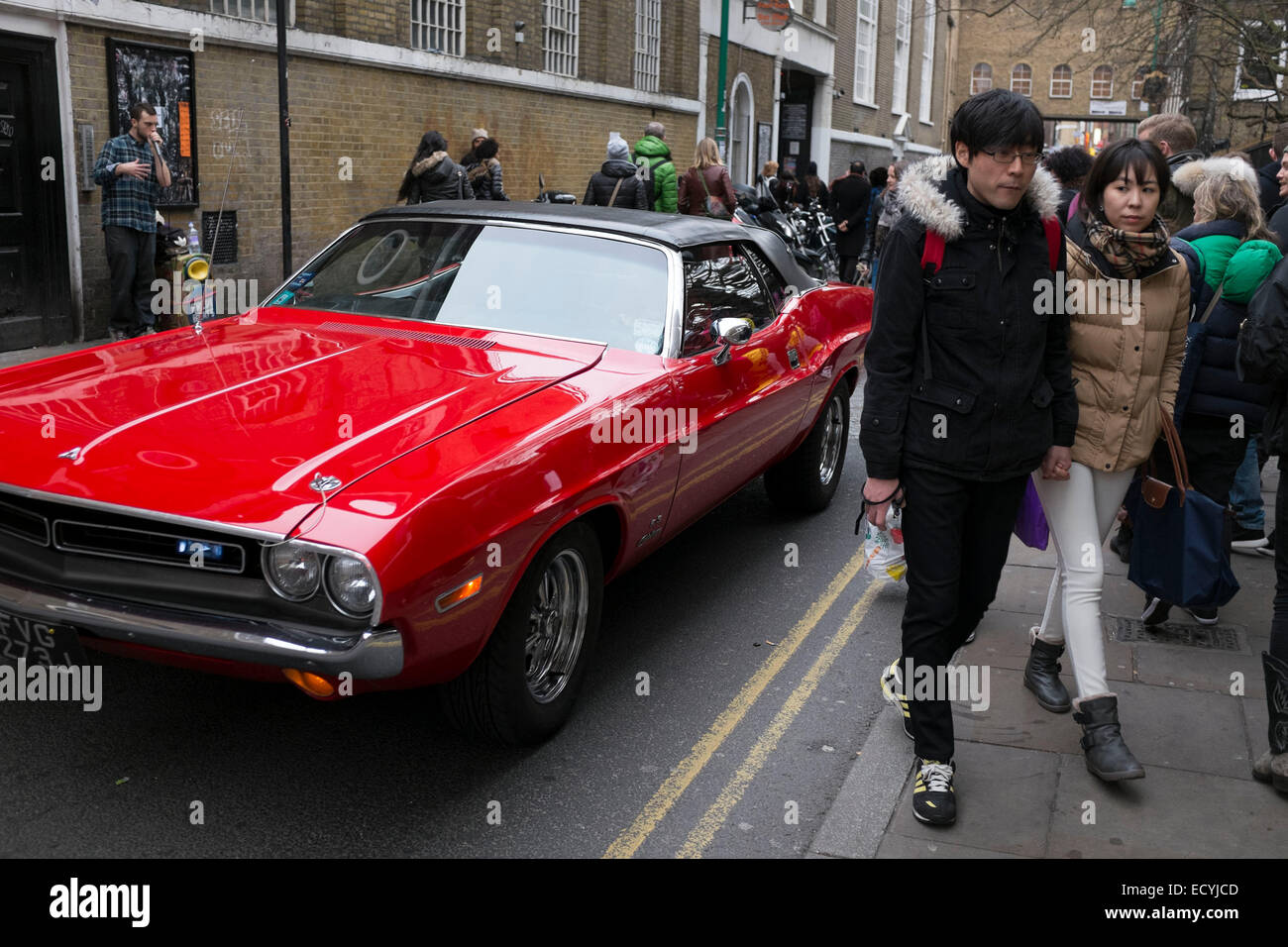 Scena di strada come un rosso classico americano auto d'epoca, passa a Brick Lane market nell'East End di Londra, Regno Unito. Foto Stock Scena di strada come un rosso classico americano auto d'epoca, passa a Brick Lane market nell'East End di Londra, Regno Unito. Foto Stock