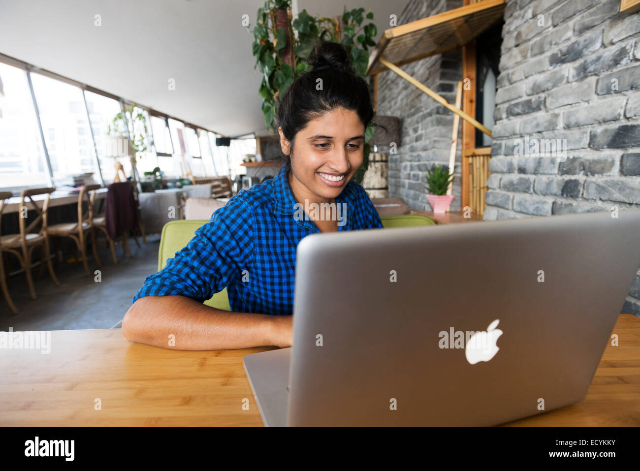 Sorridente giovane donna indiana utilizzando Apple laptop MacBook Foto Stock