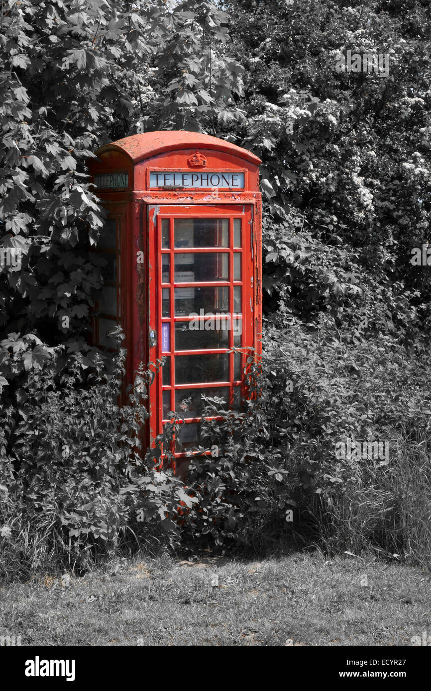 Chiudere montante mono e color pop fotografia di un singolo isolato incolto fuori uso cabina telefonica. Il colore rosso color pop contro Foto Stock