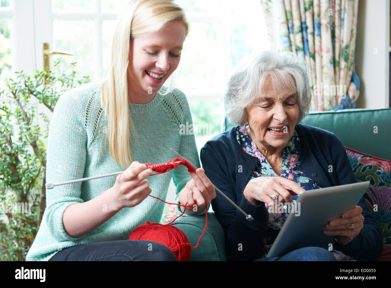 Nonna con tavoletta digitale mentre la nipote maglieria Foto Stock