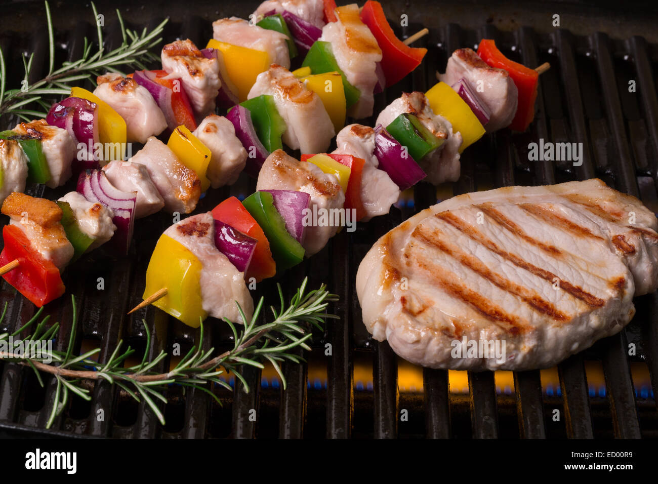 Bistecca di carne di maiale e spiedini cottura su un barbecue grill Foto Stock