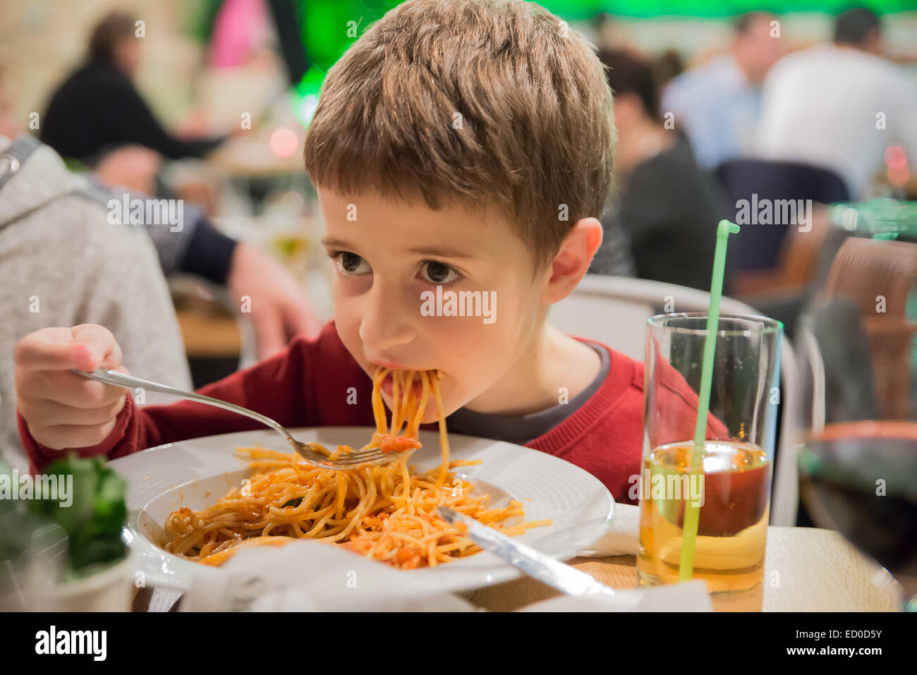 Ragazzo seduto in un ristorante mangiare spaghetti Foto Stock