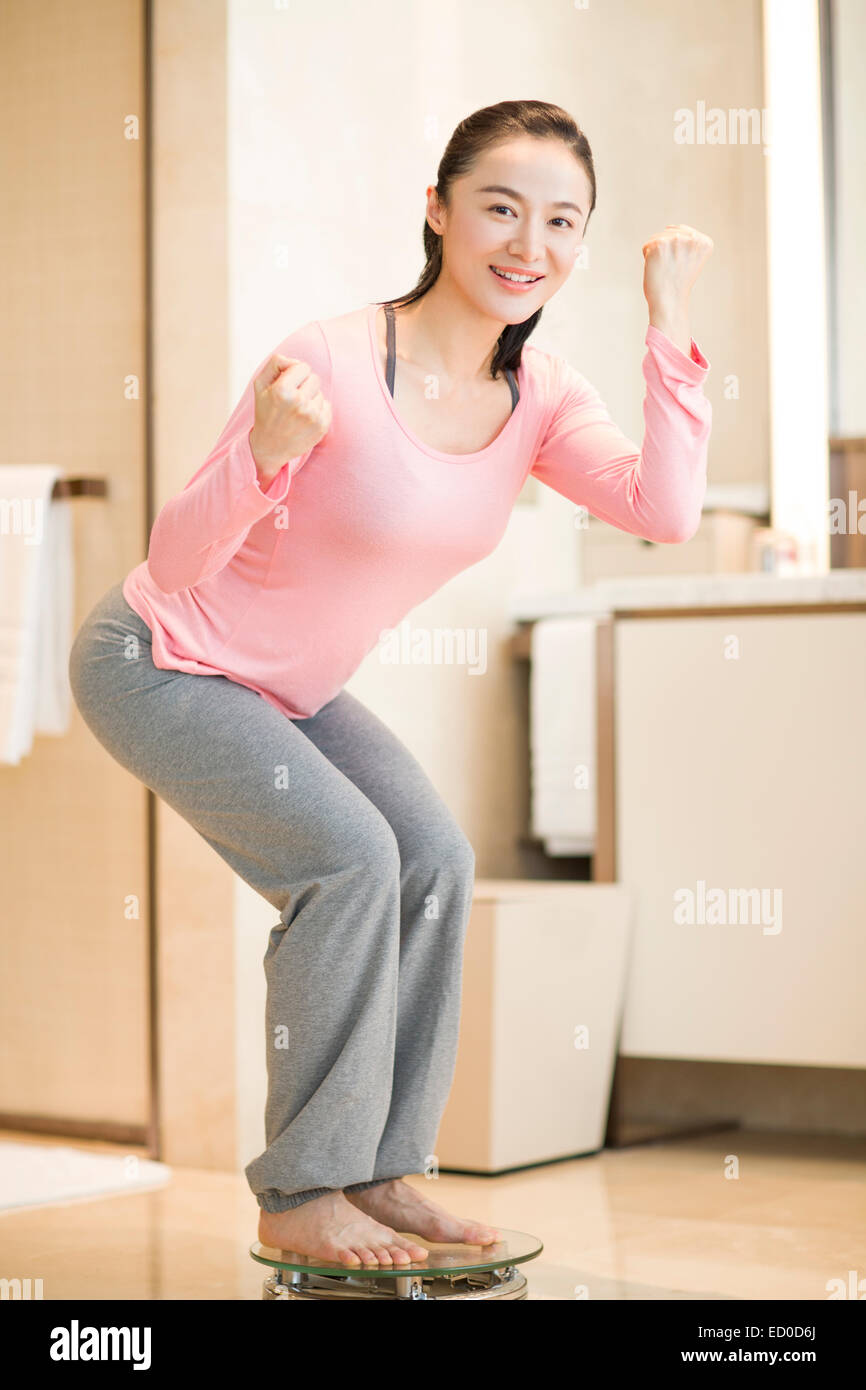 Giovane donna di peso se stessa su una scala Foto Stock