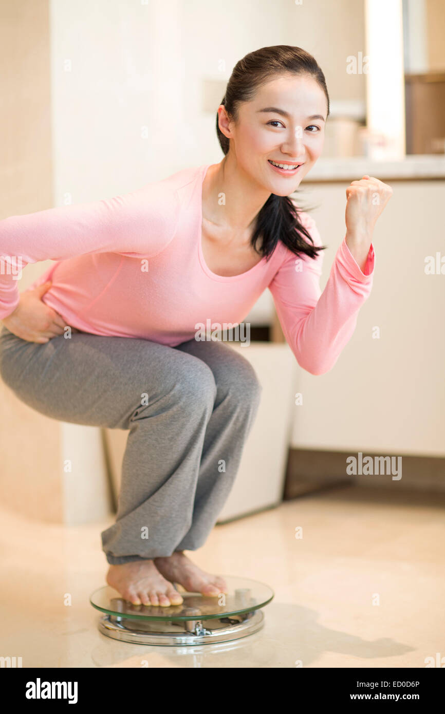 Giovane donna di peso se stessa su una scala Foto Stock