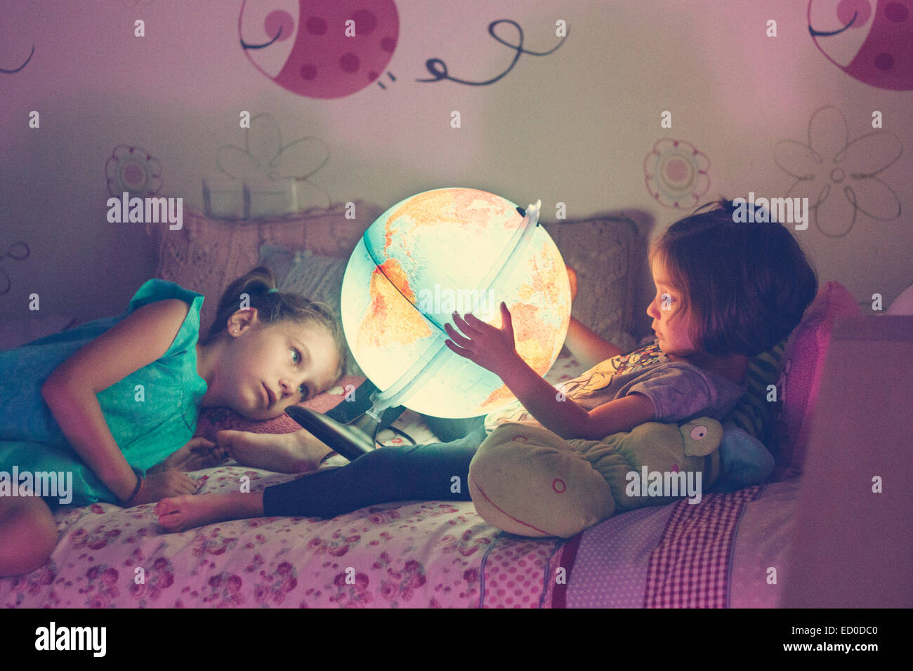 Due ragazze (2-3, 6-7) guardando accesa la lampada a forma di globo Foto Stock