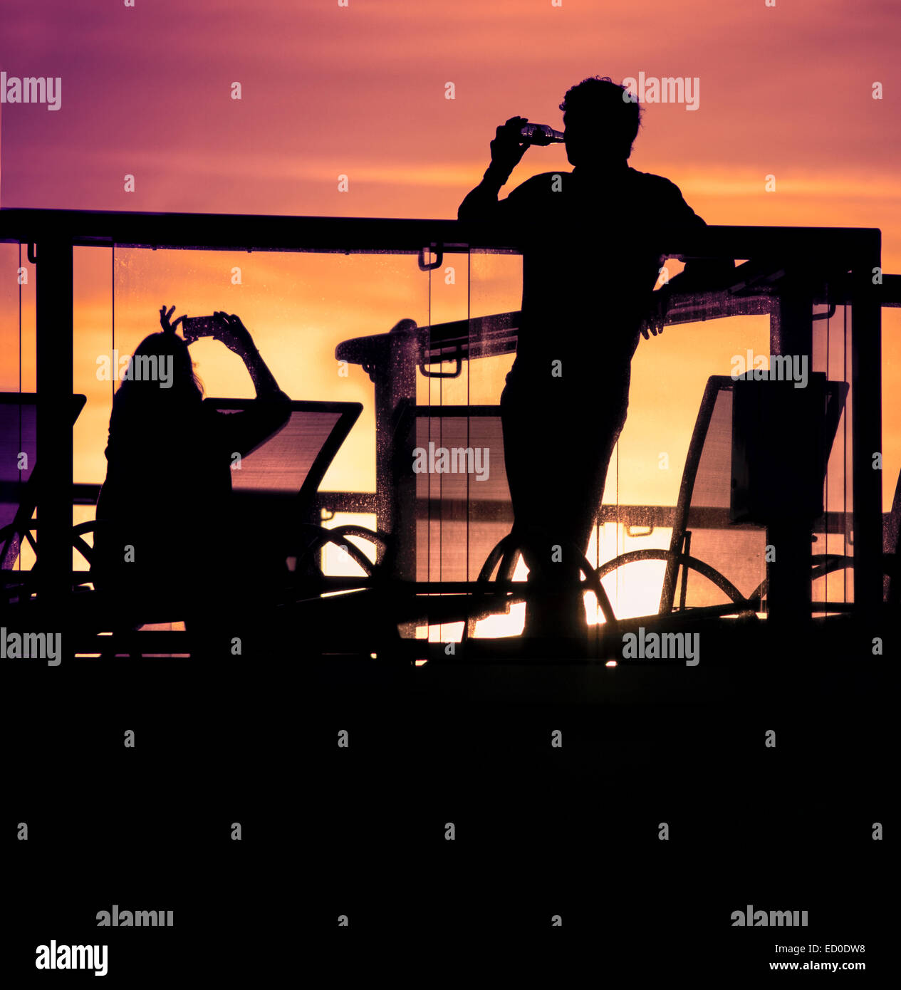 Inghilterra, Southampton, sagome di giovane rilassante sul balcone al tramonto Foto Stock