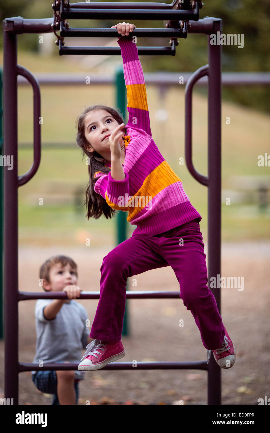 Ragazza e ragazzo che giocano su una struttura per arrampicata in un parco giochi Foto Stock