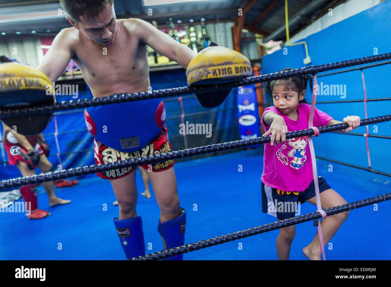 Bangkok, Bangkok, Thailandia. Xviii Dicembre, 2014. Un coach lavora con BAI THONG, 7 anni presso la palestra Kanisorn in Bangkok. Ella è stata la boxe per circa 5 mesi. La boxe Kanisorn palestra è una piccola palestra lungo la Wong Wian Yai - Samut Sakhon binari del treno. I giovani dalla vicina europee entrano in palestra per saperne di thai boxing. Muay Thai (Muai Thai) è un misto di arte marziale sviluppato in Thailandia. La Muay Thai è diffuso a livello internazionale nel ventesimo secolo quando i boxer tailandese ha sconfitto gli altri ben noti boxer. Un campionato professionale è disciplinata dal mondo Muay Thai consiglio. Muay Thai Foto Stock