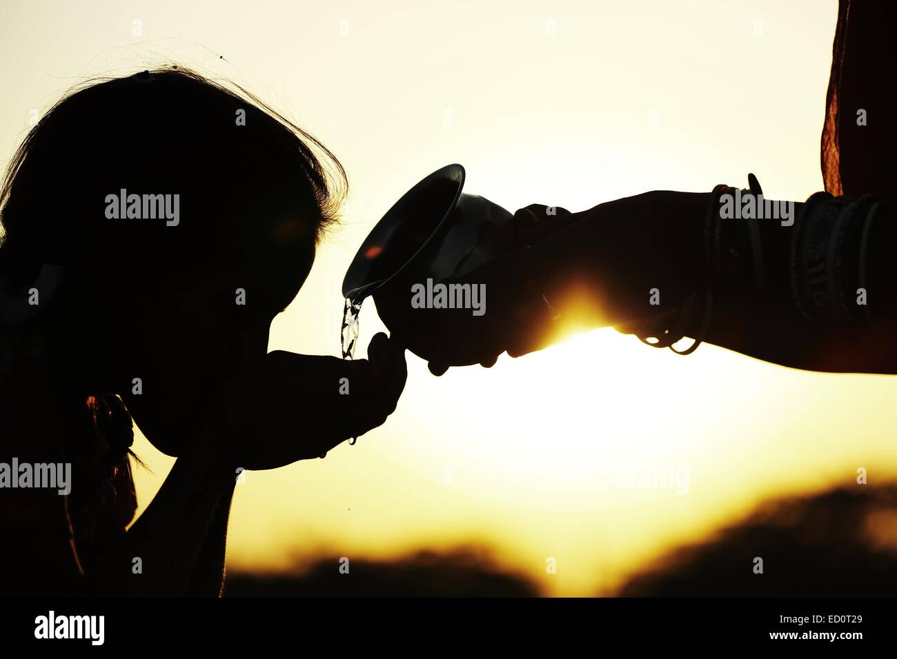 Madre indiana dando acqua a sua figlia India Foto Stock