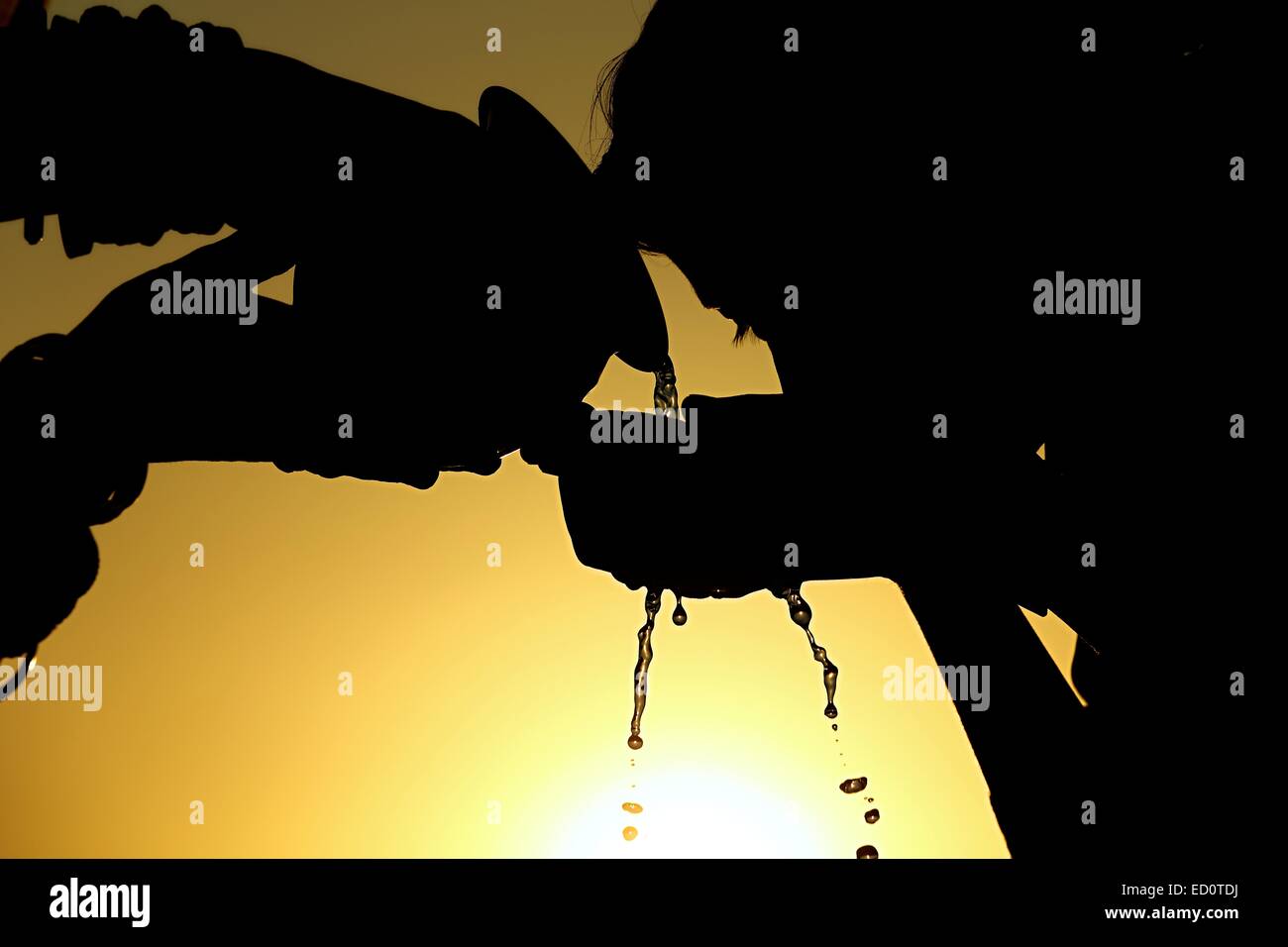 Madre indiana dando acqua potabile a sua figlia Foto Stock