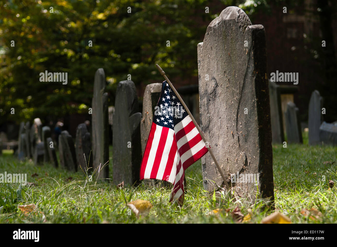 Fila di molto vecchie lapidi sulla Granary Seppellimento di massa, Boston, MA. Una tomba decorata con stelle e strisce. Foto Stock