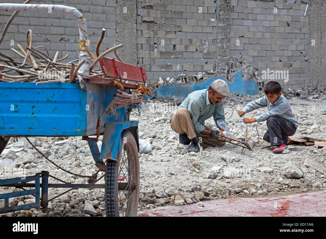Figlio aiutando padre recuperando il ferro da stiro con una sega per metalli da detriti di edificio crollato dopo il terremoto in furgone, Turchia orientale Foto Stock