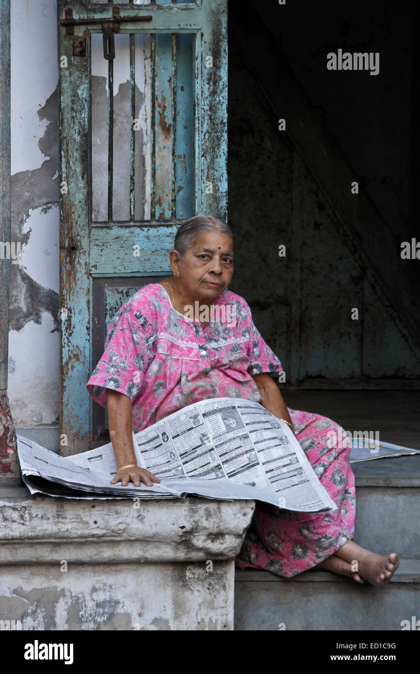 Donna quotidiano di lettura al di fuori di casa nella vecchia Ahmedabad, Gujarat, India Foto Stock