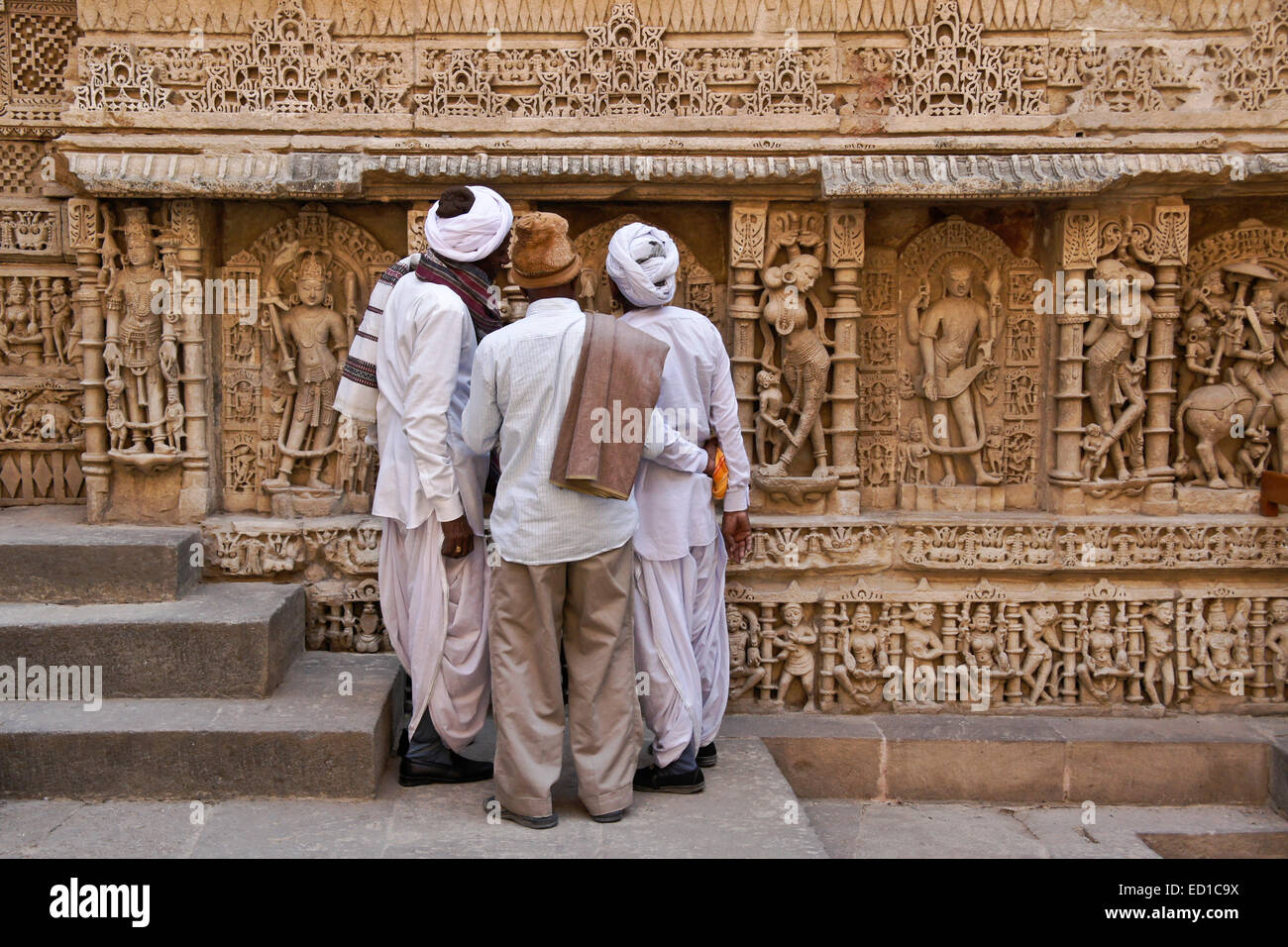 Gujarati uomini ammirando sculture ornate sulla parete di Rani-ki-Vav passo ben, Patan, Gujarat, India Foto Stock