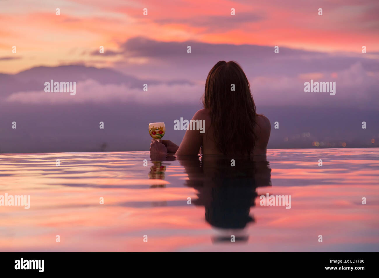 Un visitatore godersi il tramonto da una piscina all'infinito, Maui, Hawaii. (Modello rilasciato) Foto Stock