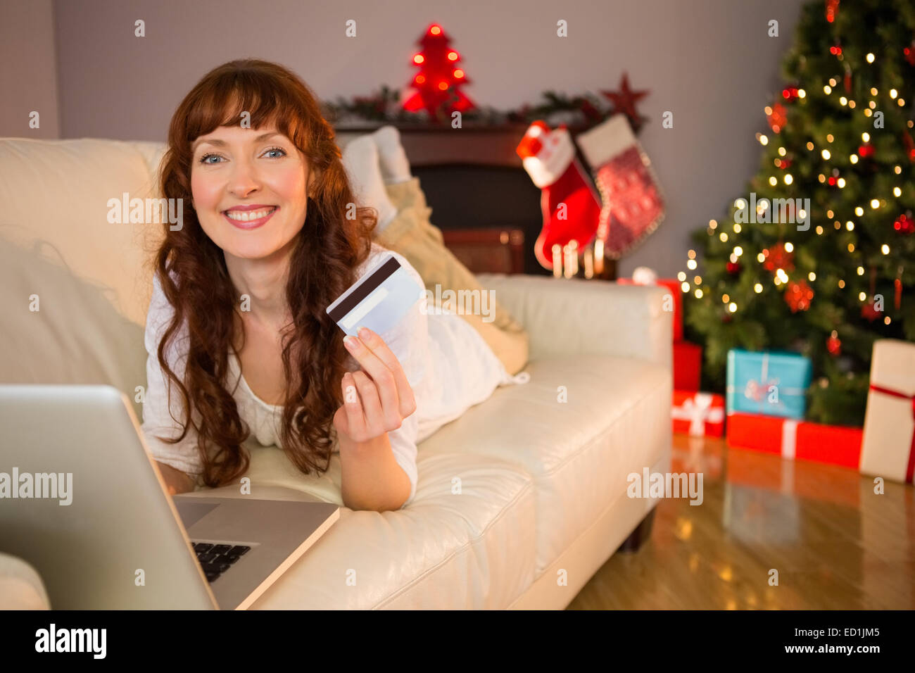 Sorridente redhead sdraiato sul lettino lo shopping online con il computer portatile Foto Stock