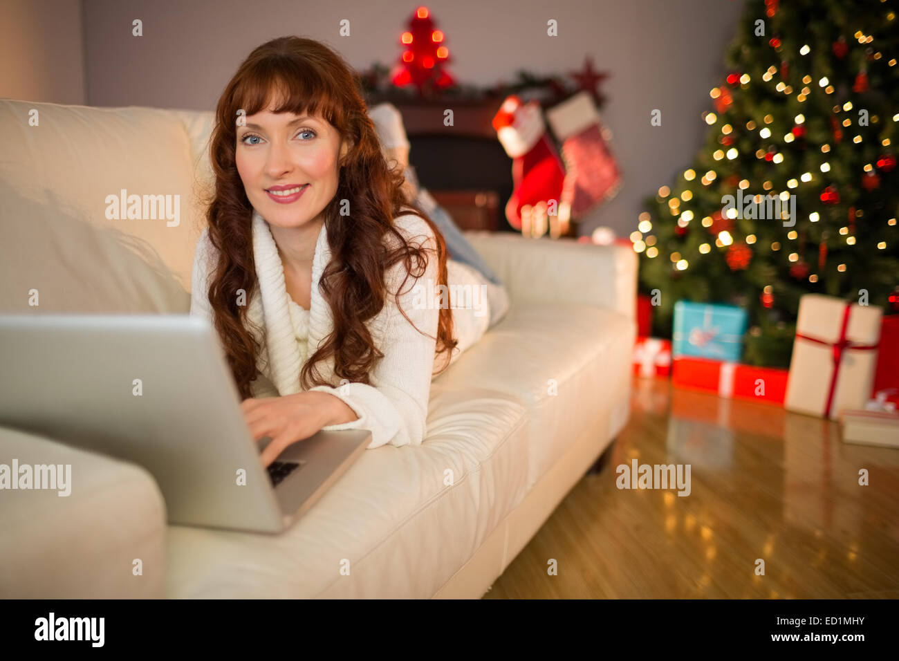 Sorridente redhead donna utilizzando laptop sul lettino a natale Foto Stock