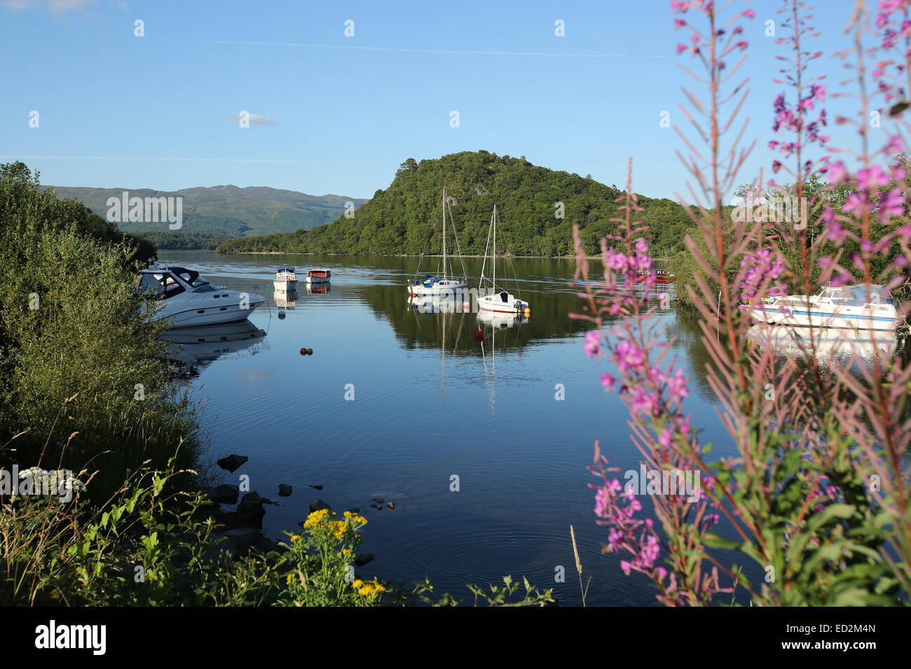 Villaggio di Luss, Scozia. Pittoresca vista estiva di imbarcazioni da diporto ormeggiata presso le sponde del Loch Lomond vicino al villaggio di Luss. Foto Stock