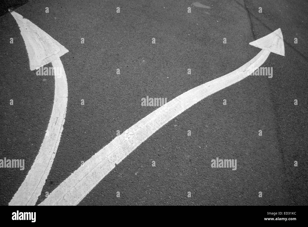 Bianco curva frecce dipinte su black tarmac Foto Stock