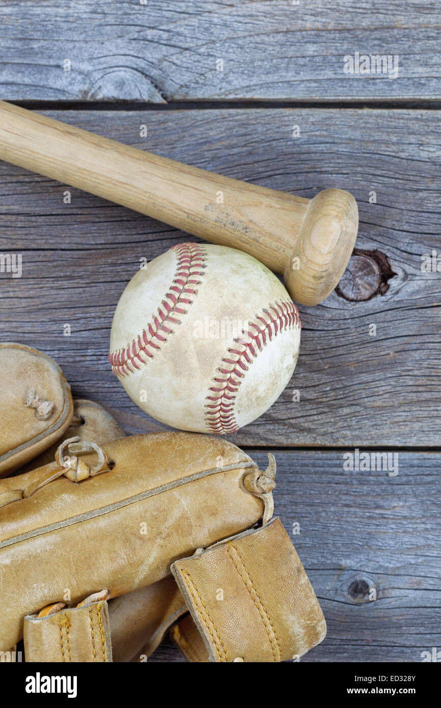 L'immagine verticale di una parziale vecchio guanto indossato, bat e utilizzato il baseball su legno rustico Foto Stock