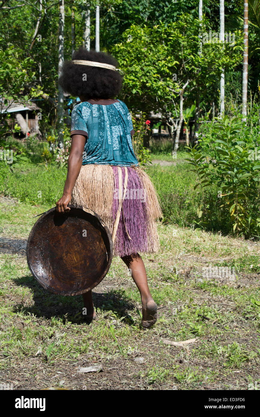 La Melanesia, Papua Nuova Guinea, Dobu isola. Donna in erba gonna con piastra in legno. Foto Stock