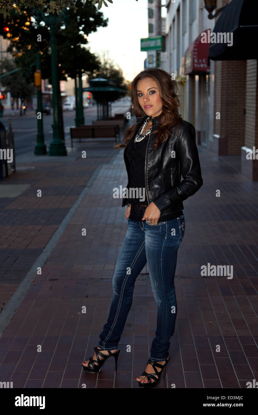 Giovane donna in giacca di pelle in piedi da solo sul marciapiede nel centro di El Paso, Texas Foto Stock