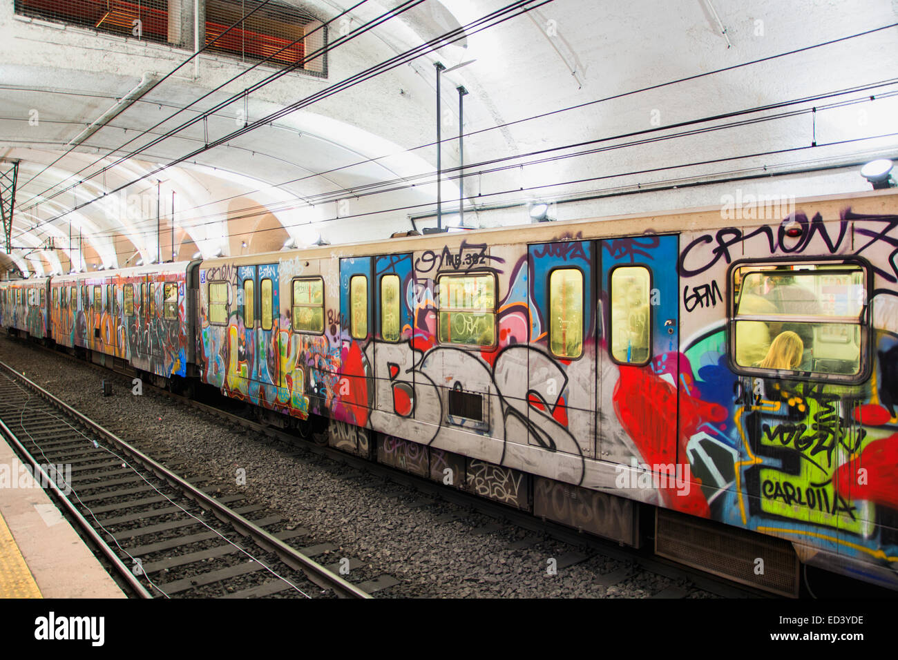 Coloratissimo graffito sui lati dei carrelli di un tubo della metropolitana treno parcheggiato in una stazione della metropolitana vista lungo la via Foto Stock