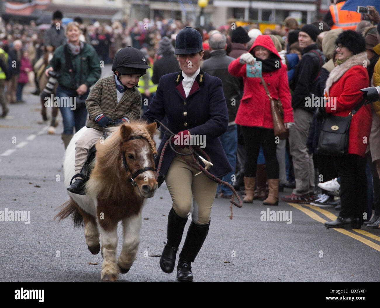 Thornbury, Gloucestershire, UK. Il 26 dicembre, 2014. Membri della Berkeley Hunt galoppo attraverso Thornbury High Street all'inizio del Boxing Day Hunt. La caccia alla volpe è ancora proibita per la caccia segue un preparato profumo. Il partito conservatore membri si terrà una votazione libera sul divieto huntingh se winns 2015 elezione. Credito: Signor Standfast/Alamy Live News Foto Stock