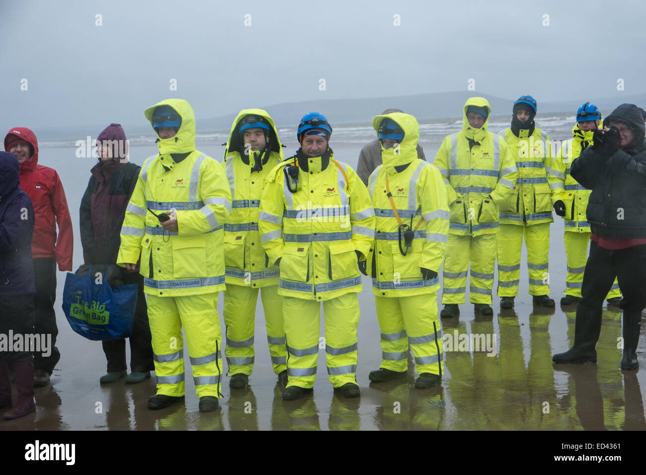 Carmarthenshire, Wales, Regno Unito. Il 26 dicembre, 2014. A Pembrey Sands,Cefn Sidan, su un molto freddo,ventoso e con heavy rain per il trentesimo anniversario di tricheco Dip. Brave nuotatori sopportare gli elementi vestiti in vari abiti fantasiosi costumi per una breve nuotata in acque gelide.Carmarthenshire,Galles,UK. Credito: Paolo Quayle/Alamy Live News guardie avvolto contro il bagnato,pioggia,piovoso,giorno e terribilmente freddo Boxing Day meteo per proteggere e conservare i nuotatori di sicuro il congelamento di acqua.giacca a vento, protettivi, impermeabili, abbigliamento, Foto Stock