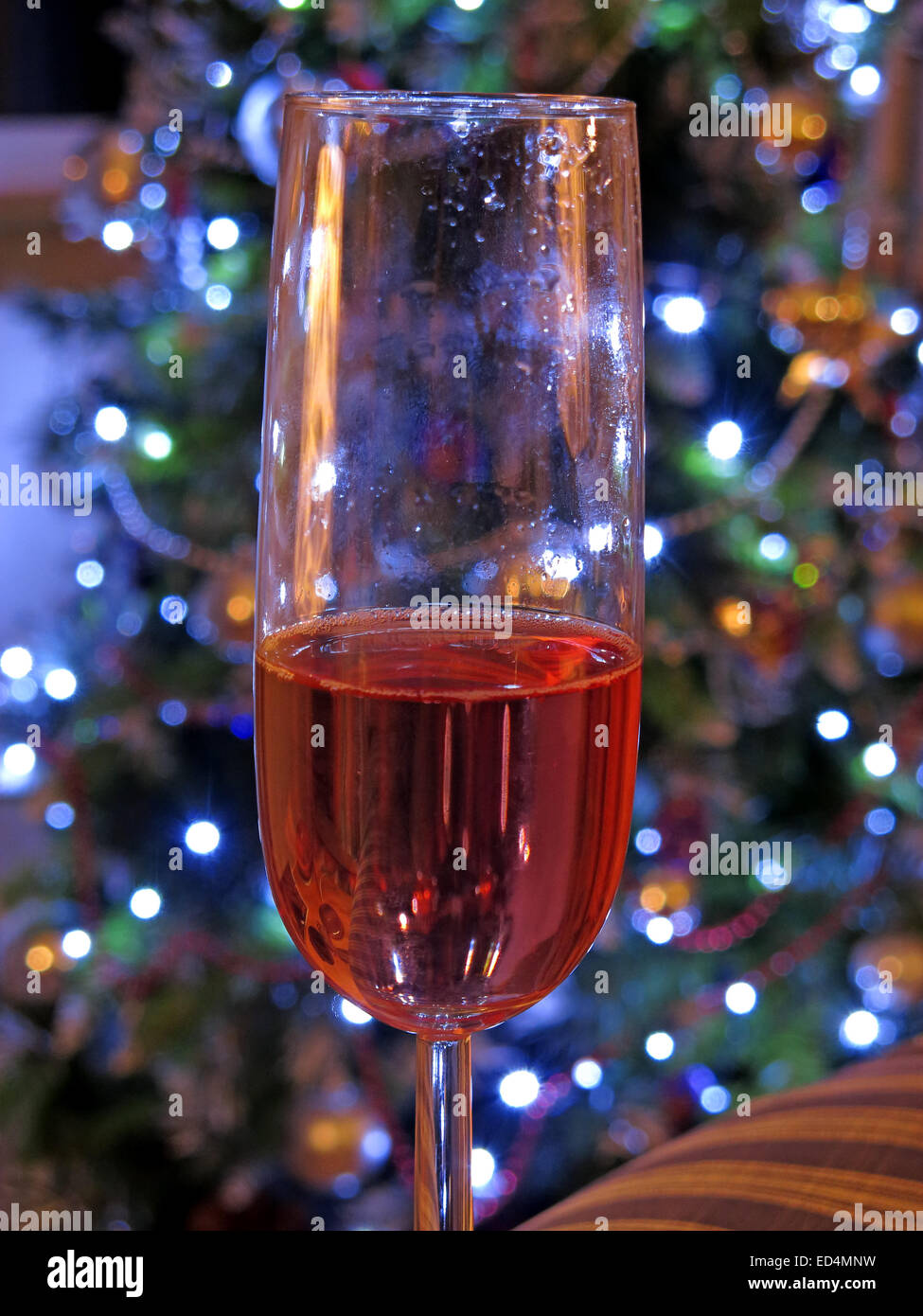 Pericoli di bere festivo, un altro bicchiere di vino rosato, a Natale, di fronte all'albero delle decorazioni - mezzo bicchiere Foto Stock